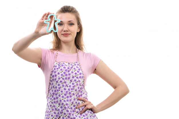 Free Photo a front view young attractive housewife in pink shirt colorful cape posing smiling holding little blue human formed toy on the white background cuisine kitchen female