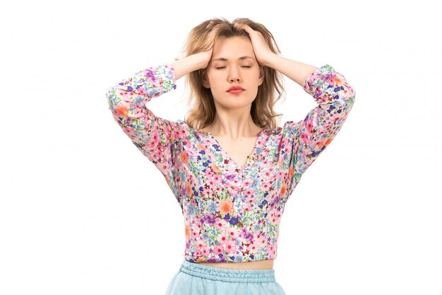 A front view young attractive lady in colorful flower designed shirt and blue skirt posing with closed eyes on the white