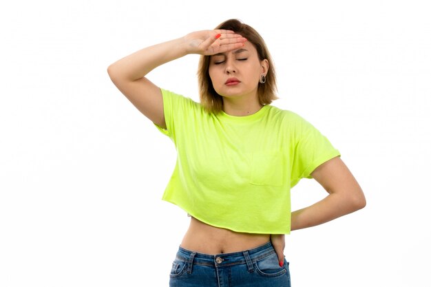 A front view young attractive lady in green shirt and blue jeans suffering from high temperature on the white