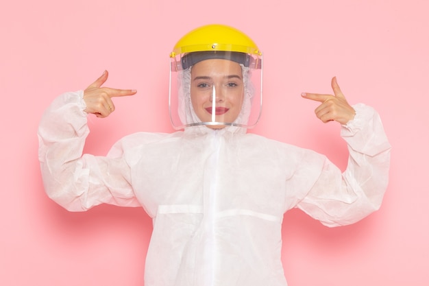 Front view young beautiful female in special white suit wearing special yellow helmet with smile on the pink space special suit  girl woman