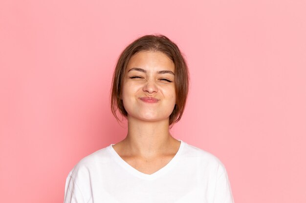 A front view young beautiful female in white shirt posing with delighted expression