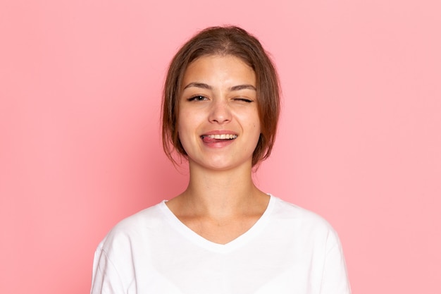 A front view young beautiful female in white shirt posing with delighted and smiling expression