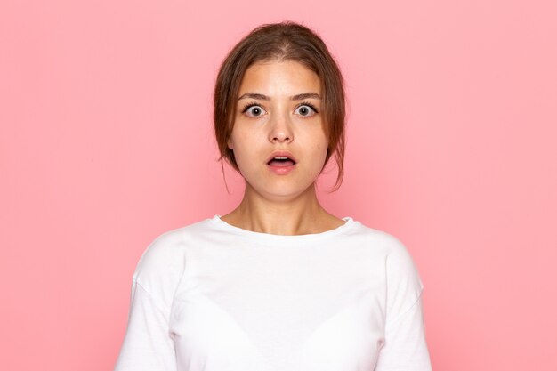 A front view young beautiful female in white shirt posing with surprised expression