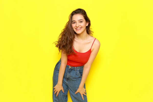 A front view young beautiful girl in red shirt and blue jeans just posing with happy expression