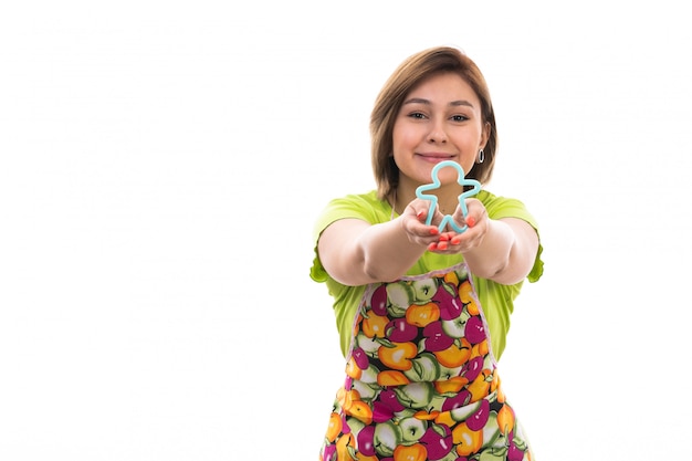 A front view young beautiful housewife in green shirt colorful cape holding blue human figure shape smiling on the white background house cleaning kitchen