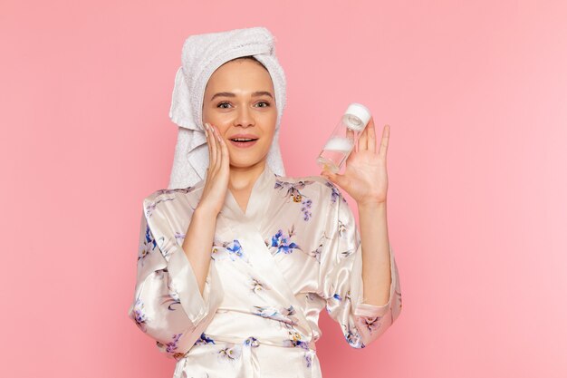 A front view young beautiful lady in bathrobe holding make-up cleaner spray