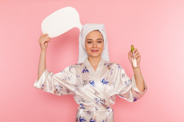 Free Photo a front view young beautiful lady in bathrobe holding white sign and spray