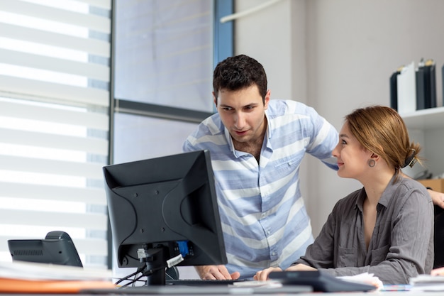 A front view young beautiful lady in grey shirt talking and discussing something with young man inside office during daytime building job activity