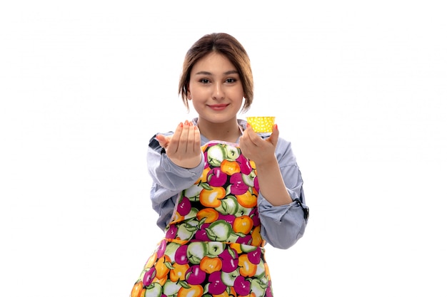 Free photo a front view young beautiful lady in light blue shirt and colorful cape holding yellow cake pans happy smiling expression