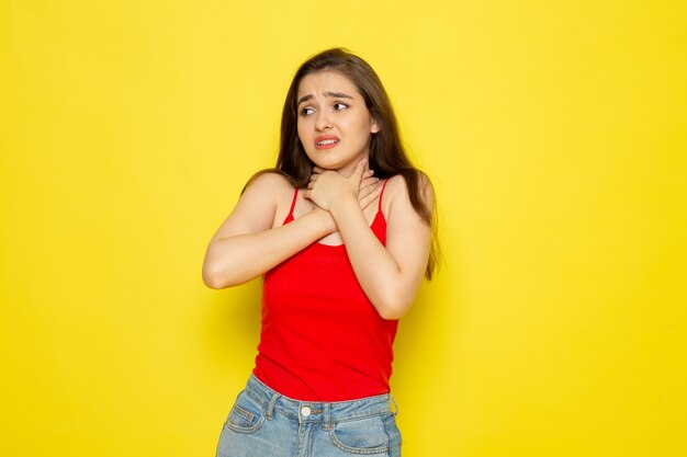 A front view young beautiful lady in red shirt and blue jeans chocking herself