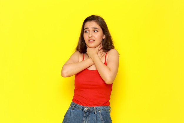 A front view young beautiful lady in red shirt and blue jeans chocking herself