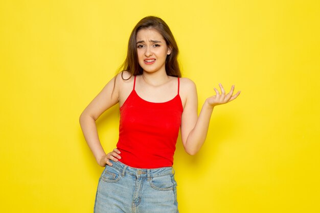 A front view young beautiful lady in red shirt and blue jeans posing