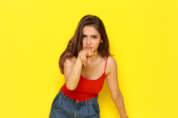 A front view young beautiful lady in red shirt and blue jeans with angry expression