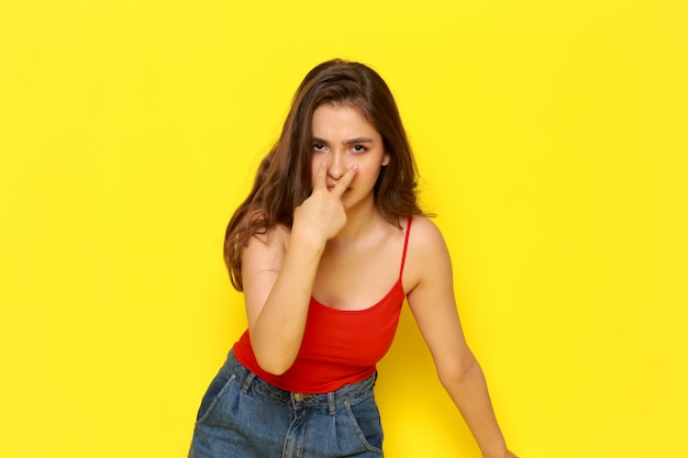 A front view young beautiful lady in red shirt coat and blue jeans posing with caution expression