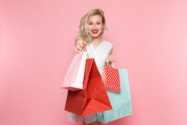 Free photo a front view young beautiful lady in white dress holding shopping packages with smile on her face