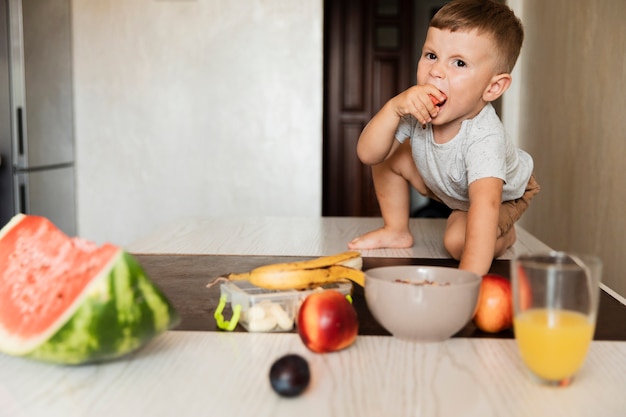 Front view young boy eating fruit