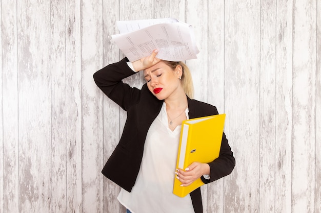 Free Photo front view young businesswoman in strict clothes black jacket holding files and documents on white surface