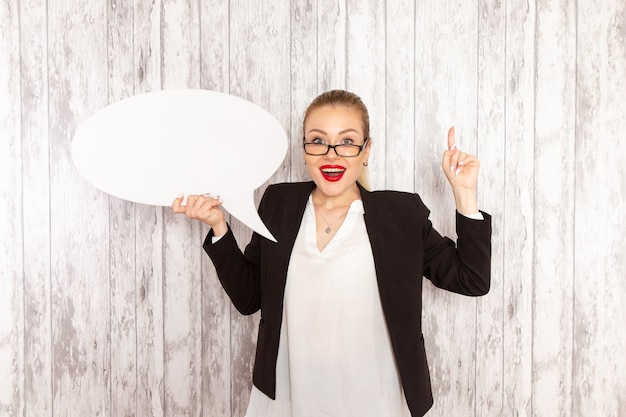 Free photo front view young businesswoman in strict clothes black jacket holding huge white sign on white desk