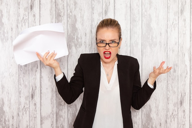 Front view young businesswoman in strict clothes black jacket reading document on the white surface