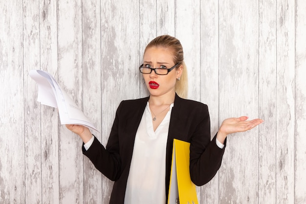 Front view young businesswoman in strict clothes black jacket reading document on white surface