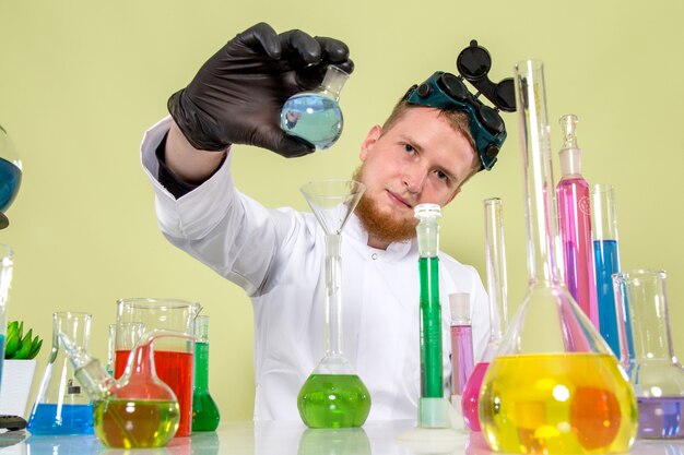 Front view young chemist pointing out his little flask