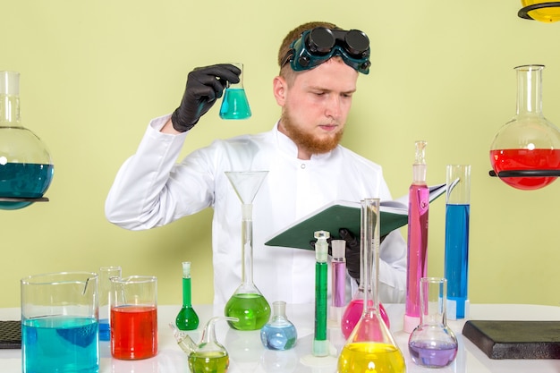 Front view young chemist reading about light blue chemical