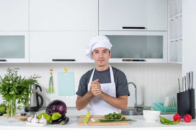 Front view young cook in uniform hands clasped