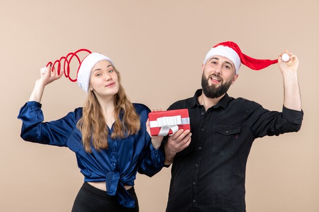 Front view young couple both holding males present on pink background gift holiday photo new year christmas