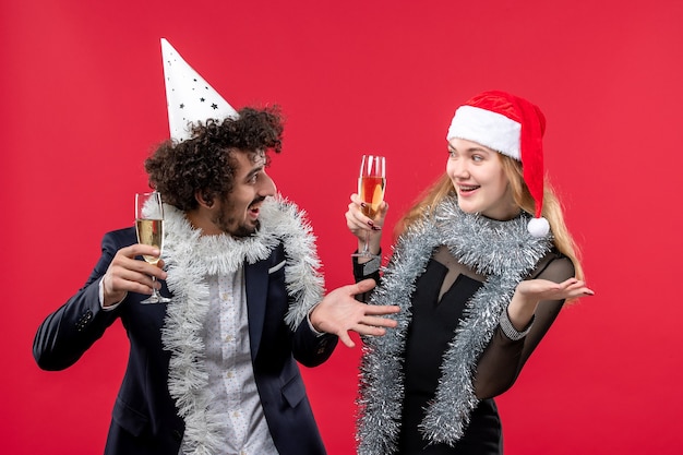 Free photo front view young couple celebrating new year on red wall holidays christmas love