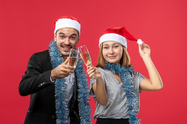 Front view young couple celebrating new year on the red wall love christmas party drink