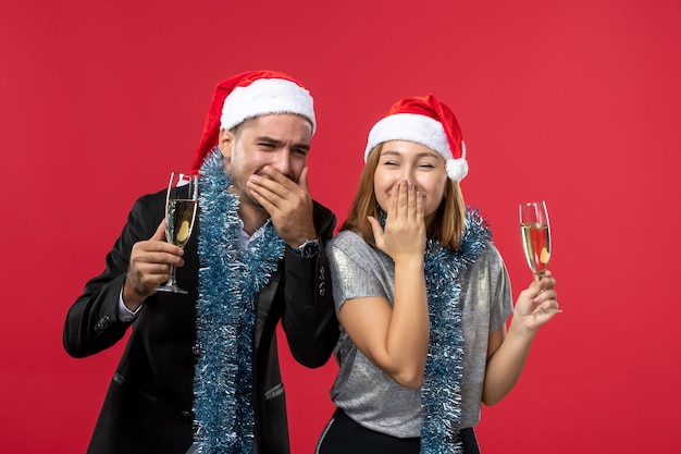 Free photo front view young couple celebrating new year on the red wall love christmas party drink