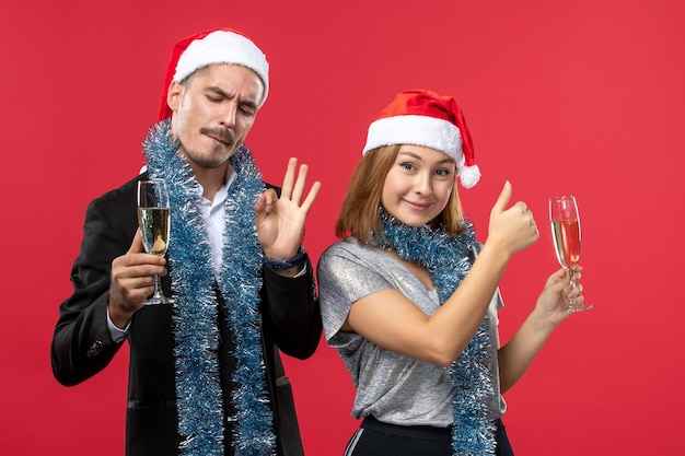 Free photo front view young couple celebrating new year on red wall love christmas party drinks