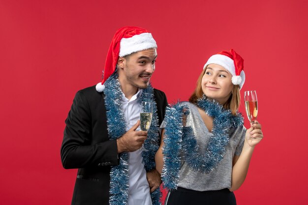 Front view young couple celebrating new year on a red wall love christmas party