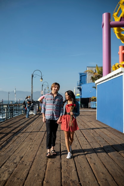 Free Photo front view of young couple on a date walking while holding hands at the amusement park