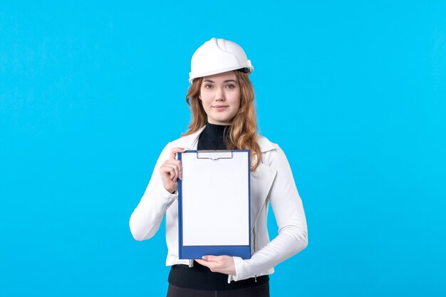 Front view young female architect in helmet on a blue