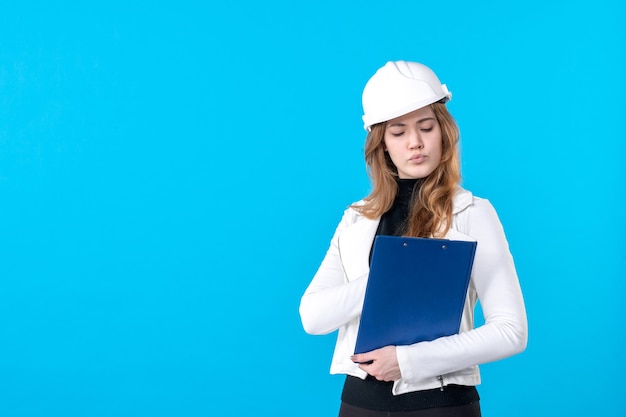 Front view young female architect in helmet on blue