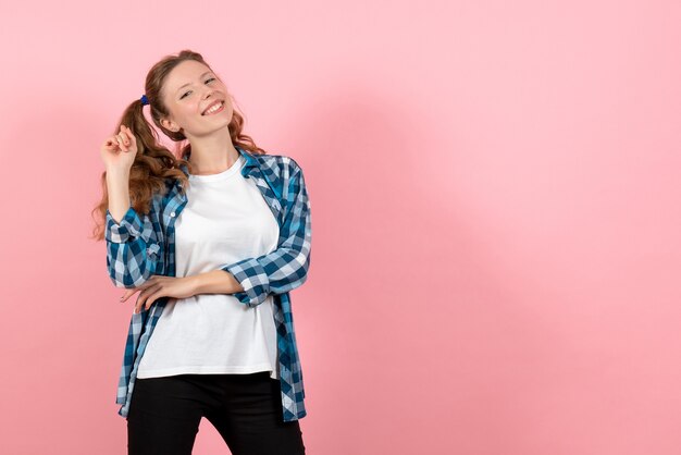 Front view young female in blue checkered shirt posing on pink background woman kid youth color emotion model