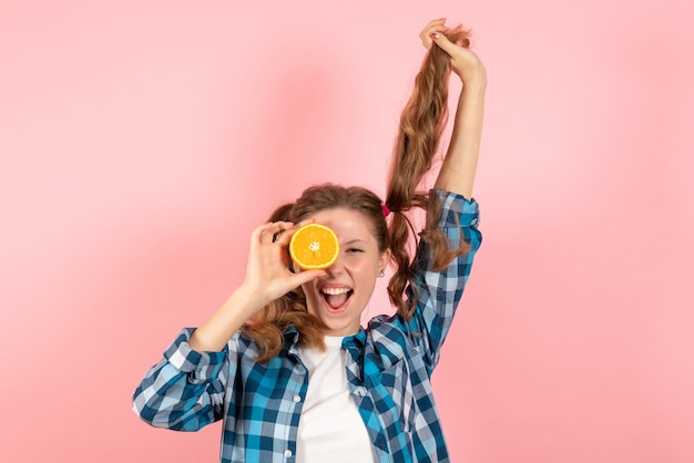 Free Photo front view young female in blue checkered shirt posing with orange on the pink background woman human emotion model fashion girl