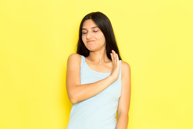 A front view young female in blue shirt posing on the yellow background girl pose model