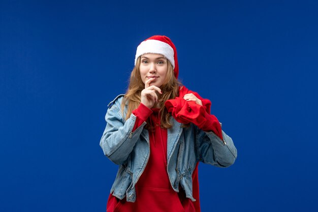 Front view young female carrying bag full of presents on blue desk color emotion christmas