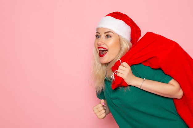 Free Photo front view young female carrying red bag with presents on the pink wall model holiday xmas new year photo color santa