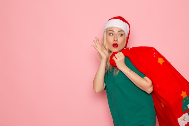 Free Photo front view young female carrying red bag with presents on pink wall model xmas new year photo color santa holidays