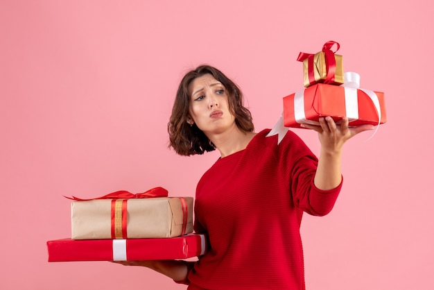 Front view young female carrying xmas presents on pink 