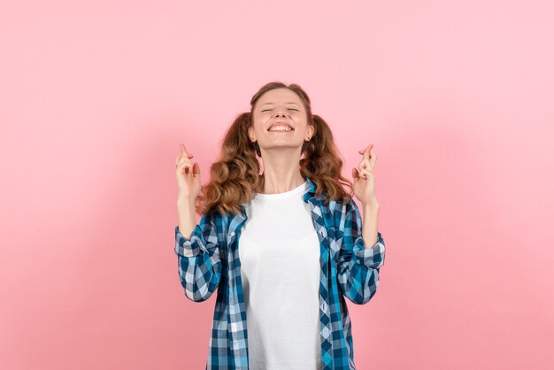 Front view young female in checkered shirt posing and crossing her fingers on pink background woman youth color emotions kid model