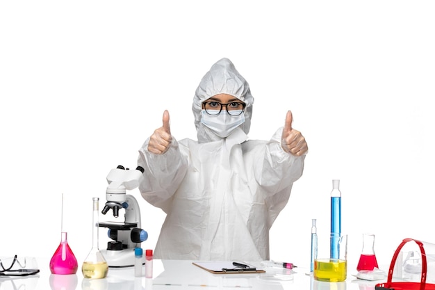 Front view young female chemist in special protective suit just sitting with solutions on a white background virus lab covid chemistry health