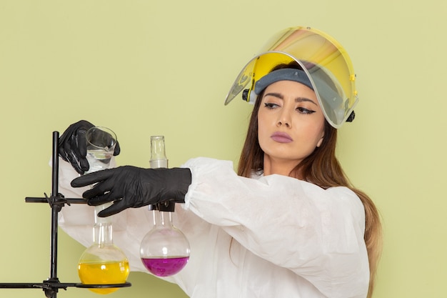 Free Photo front view young female chemist in special protective suit working with different solutions on green wall job chemical lab chemistry female science