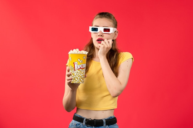 Free Photo front view young female at cinema holding popcorn on the red wall movies theater cinema snack female fun film