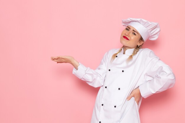 Front view young female cook in white cook suit posing all the way on the pink space cook cuisine job work  photo