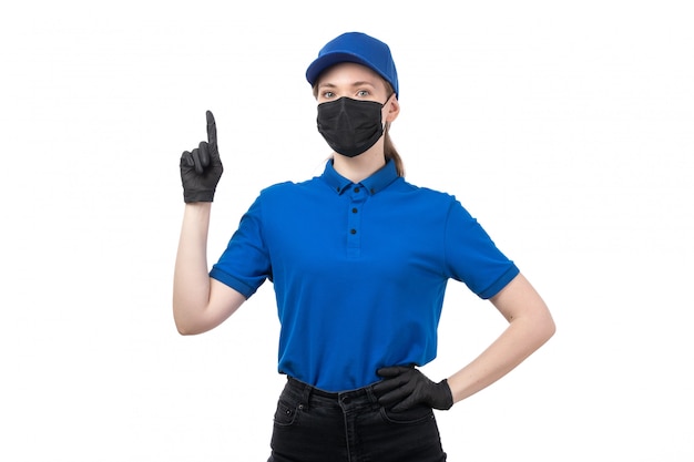 Free Photo a front view young female courier in blue uniform black gloves and black mask posing with her hands