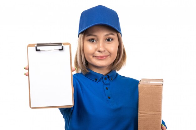 A front view young female courier in blue uniform holding food delivery package and notepad for signatures